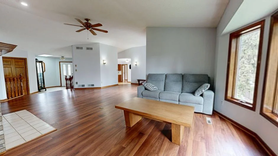 Two women in red overalls vacuuming and sweeping a modern living room.